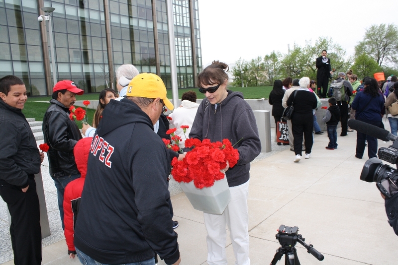 Handing out flowers to represent the 389 workers detained in the raid.JPG